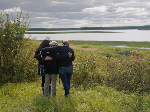 A group of people hugging in the grass  Description automatically generated